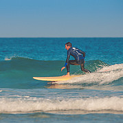 kursant utrzymuje stabilną pozycję na desce, surfując małą zieloną falę