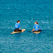 uczestnik kursu surfingu siedzi na desce w line-upie i wypatruje najlepszej fali