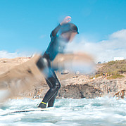 dziecko wstaje na desce i łapie swoją pierwszą falę podczas lekcji surfingu